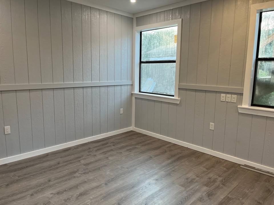 3505 Lone Man Mountain Road, Unit A Wimberley, TX 78676 - Photo 8 of 11 Well-lit room with wood paneling and sleek plank flooring, offering a fresh canvas for your personal touch.