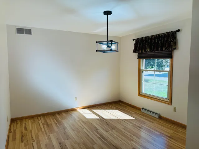 a dining room with a window and wooden floor