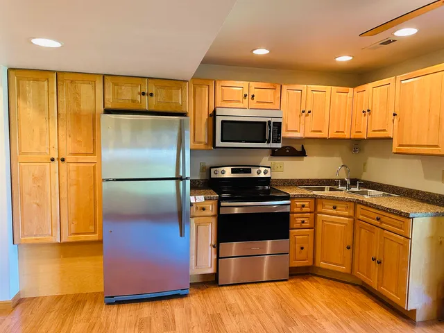 a kitchen with stainless steel appliances granite countertop a refrigerator a sink and a stove