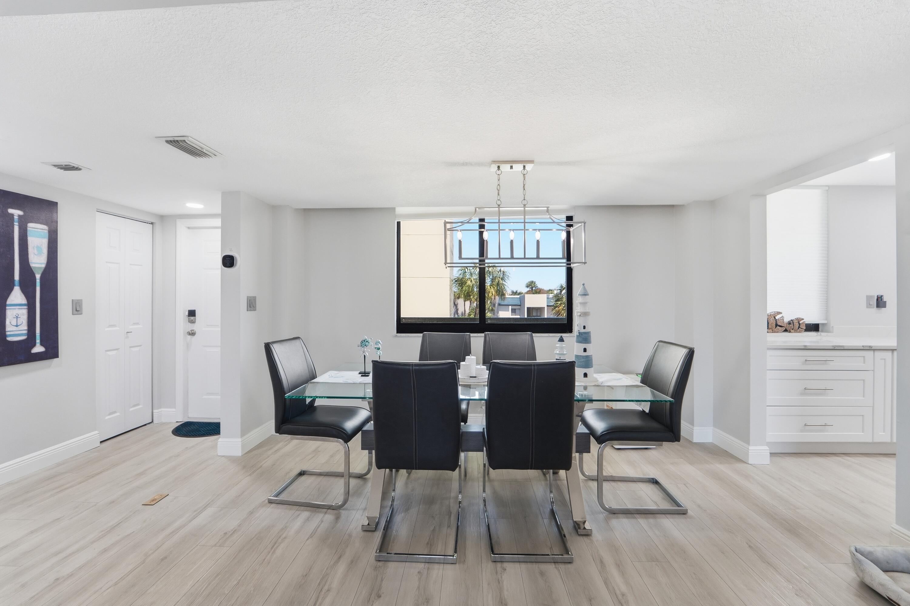 1605 Highway 1, Unit 303M1 Jupiter, FL 33477 - Photo 12 of 42 a view of a dining room with furniture a chandelier and wooden floor