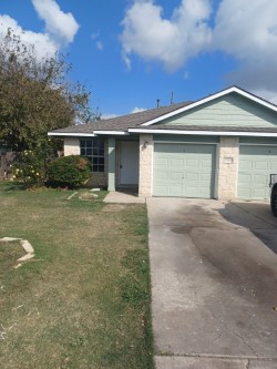 Ranch-style house with driveway, a garage, and a front lawn