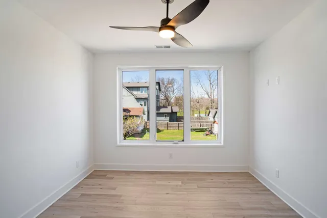 an empty room with window and ceiling fan