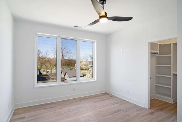a view of an empty room with a window and wooden floor