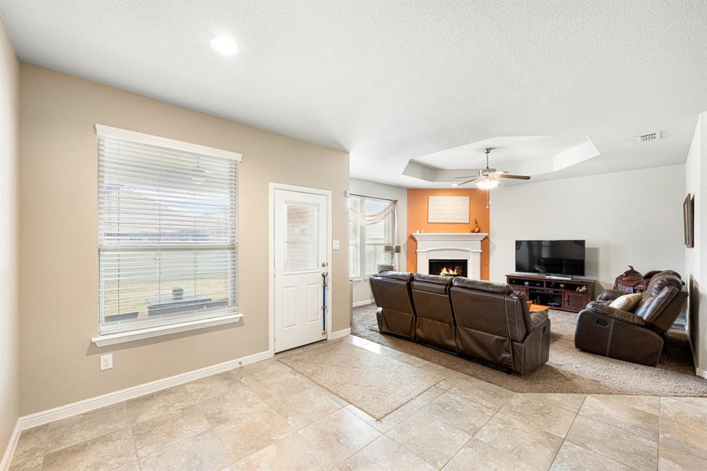 916 Falcon Road Argyle, TX 76226 - Photo 19 of 37 Tiled living room featuring a raised ceiling and ceiling fan