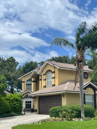 a view of a white house with a small yard and a large tree