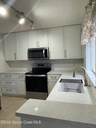 a kitchen with granite countertop a stove a sink and a microwave