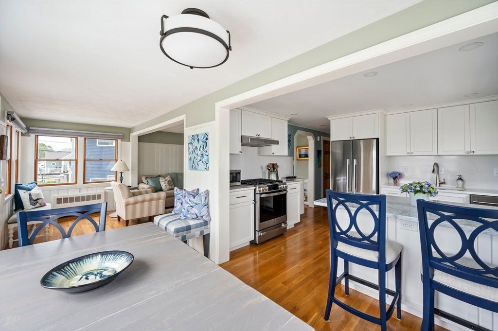 22 E Street Hull, MA 02045 - Photo 6 of 20 a kitchen with stainless steel appliances granite countertop a stove top oven a sink a dining table and chairs with wooden floor