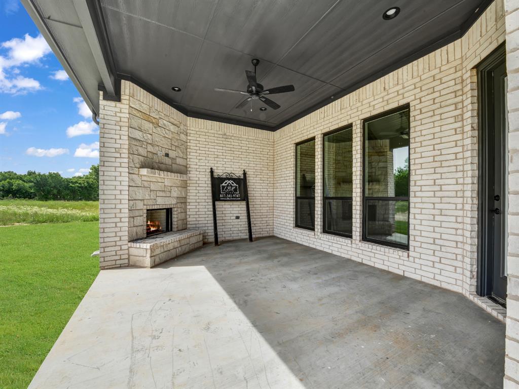 143 Desperado Way Weatherford, TX 76088 - Photo 6 of 36 View of patio / terrace featuring an outdoor stone fireplace and ceiling fan