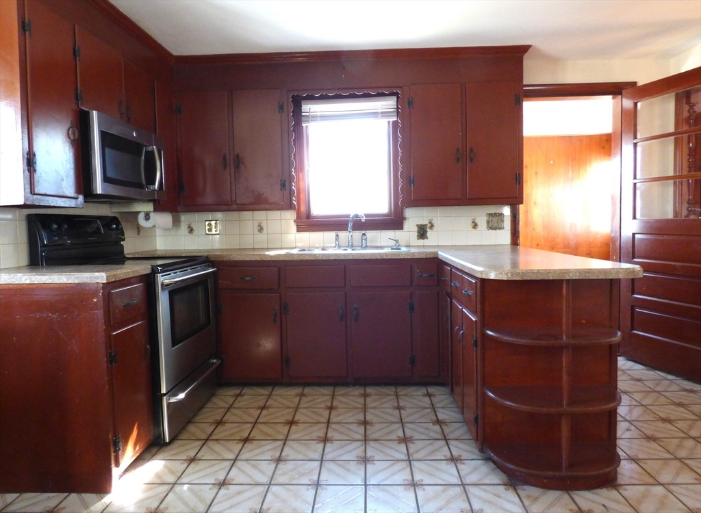 259 Prospect Street Ludlow, MA 01056 - Photo 7 of 30 a kitchen with a sink a stove a microwave and cabinets