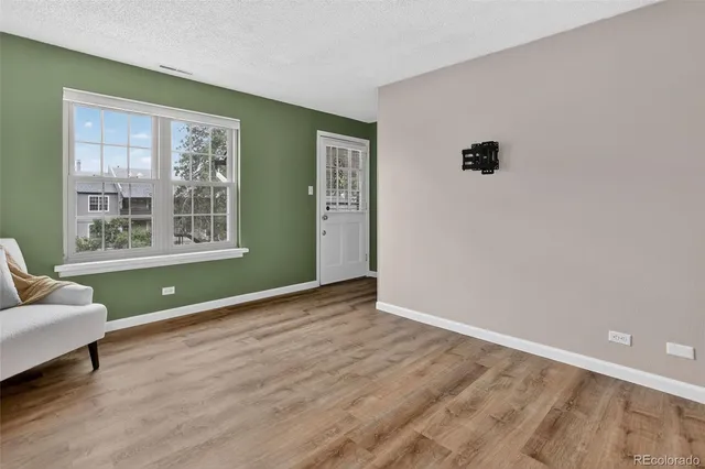 a view of an empty room with a window and wooden floor