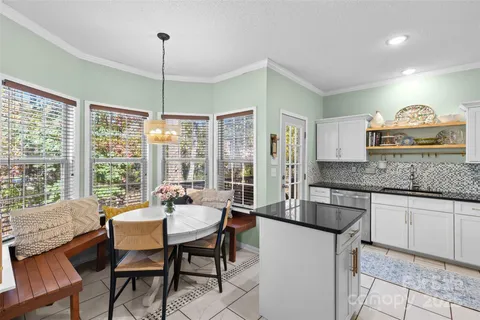 a dining hall with stainless steel appliances granite countertop a stove a sink a dining table and chairs