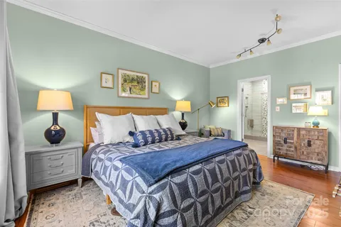 a bedroom with a bed a dresser and painting on the wall