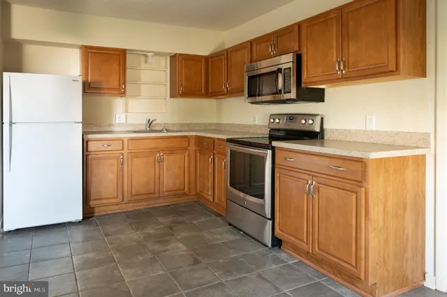 a kitchen with stainless steel appliances granite countertop a refrigerator stove top oven and sink