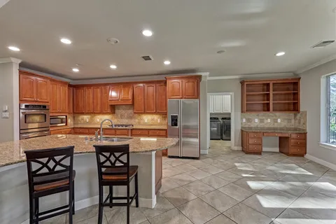 a kitchen with stainless steel appliances granite countertop a stove top oven a sink dishwasher a dining table and chairs with wooden floor
