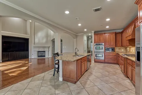 a kitchen with stainless steel appliances granite countertop a stove top oven a sink dishwasher and a refrigerator