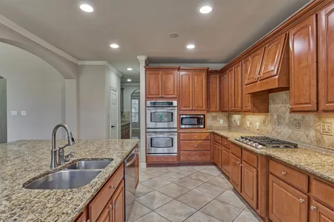 a kitchen with kitchen island granite countertop a sink stainless steel appliances and cabinets