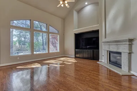 a view of an empty room with wooden floor fireplace and a window