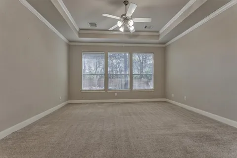 an empty room with a chandelier fan and windows