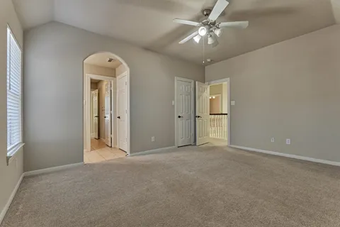 an empty room with chandelier fan and windows