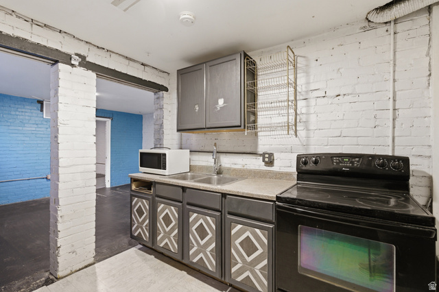 869 West Center Street Provo, UT 84601 - Photo 28 of 32 Kitchen with black electric range oven, brick wall, gray cabinetry, light countertops, and white microwave