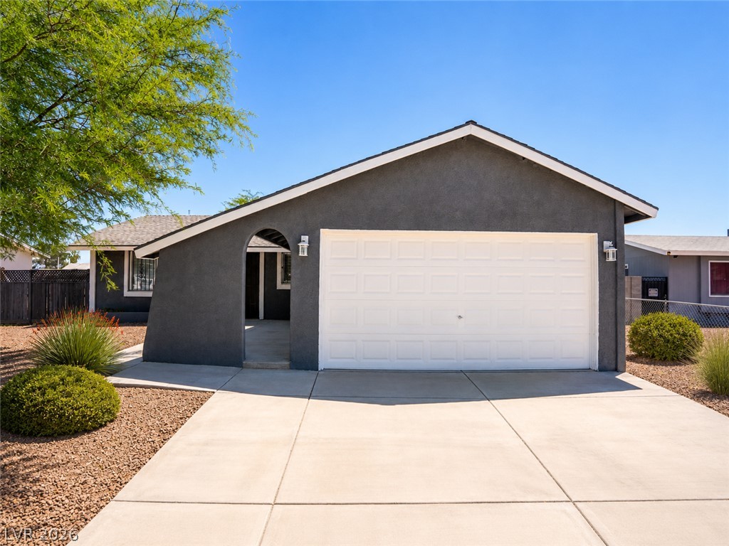 2870 South Sandhill Road Las Vegas, NV 89121 - Photo 10 of 64 A dark gray stucco home with a bright white garage door, framed by a concrete driveway and simple landscaping.