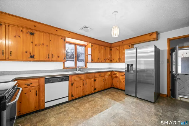 a large kitchen with stainless steel appliances granite countertop a refrigerator a sink dishwasher a stove and a refrigerator