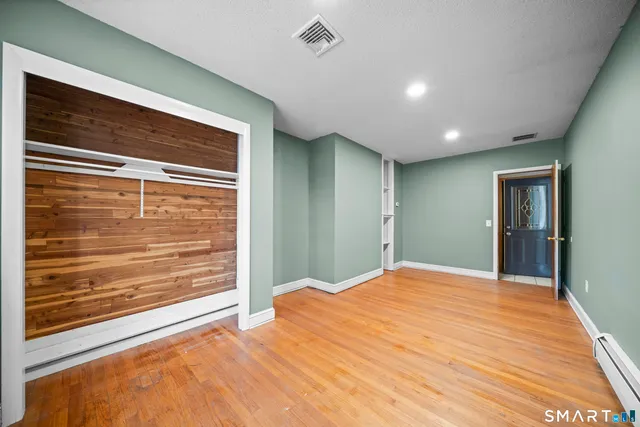 a view of an empty room with wooden floor and a window