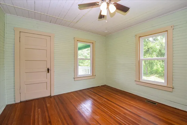 a view of an empty room with a window and wooden floor