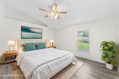 a bedroom with a large bed chandelier and a window