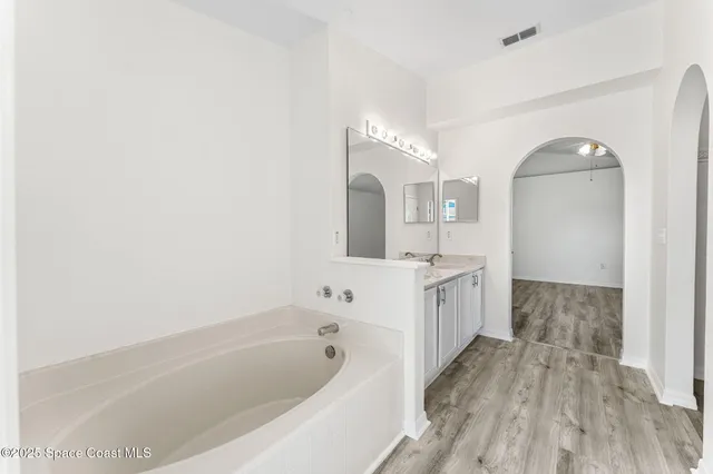 a bathroom with a bathtub a mirror a double vanity sink and vanity