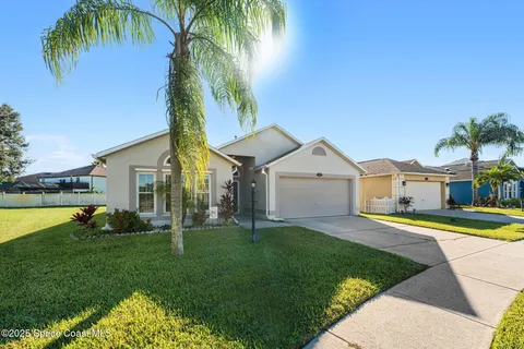 a front view of a house with a yard and palm tree