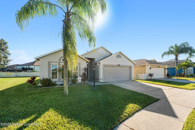 a front view of a house with a yard and palm tree