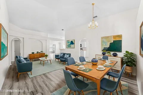 a view of a dining room with furniture a rug and wooden floor