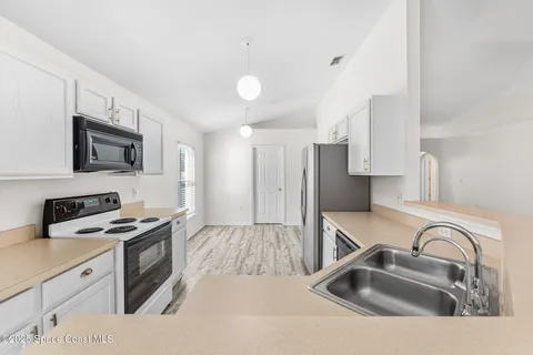 a kitchen with stainless steel appliances a sink a stove a microwave cabinets and a counter top space