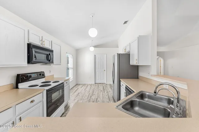 a kitchen with stainless steel appliances a sink a stove a microwave cabinets and a counter top space