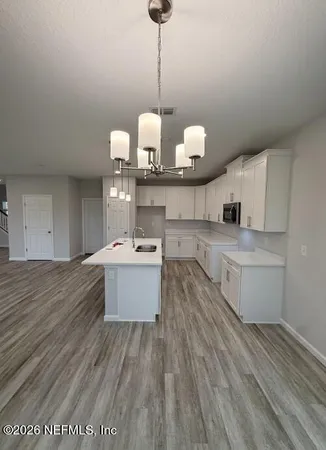 a large kitchen with kitchen island white cabinets and stainless steel appliances