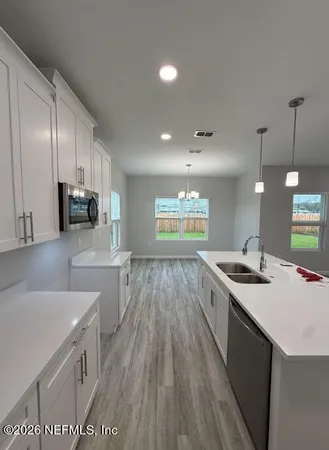 a large white kitchen with wooden floor and stainless steel appliances