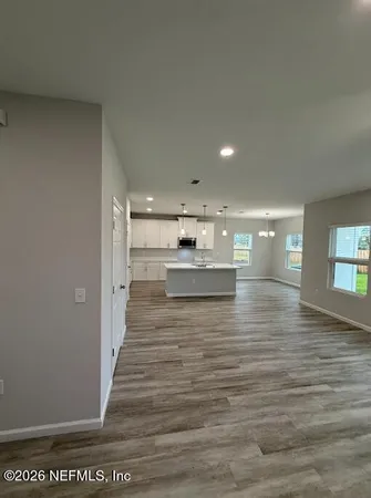 a view of a kitchen with kitchen island a sink wooden floor and a refrigerator