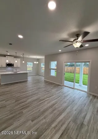 a view of an empty room with a window and wooden floor