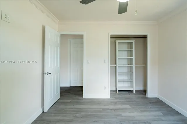 a view of an empty room with wooden floor and closet