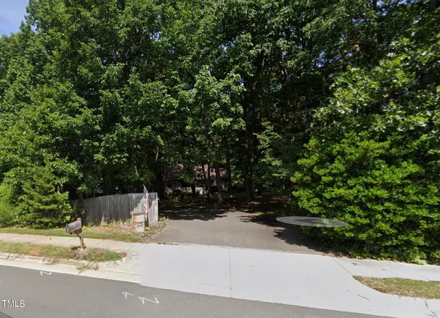 a backyard of a house with large trees and plants