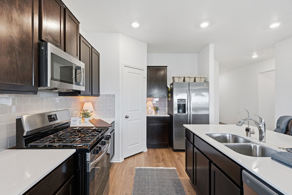 1233 Sweetspire Street Leander, TX 78641 - Photo 12 of 40 A well-appointed kitchen features dark cabinetry, bright countertops and modern stainless steel appliances. Ask for details about the new appliances.