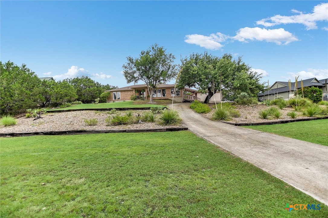 60 Crazy Cross Road Wimberley, TX 78676 - Photo 17 of 20 A long circular concrete driveway leads to a classic brick home nestled amidst mature trees and landscaped terraces.
