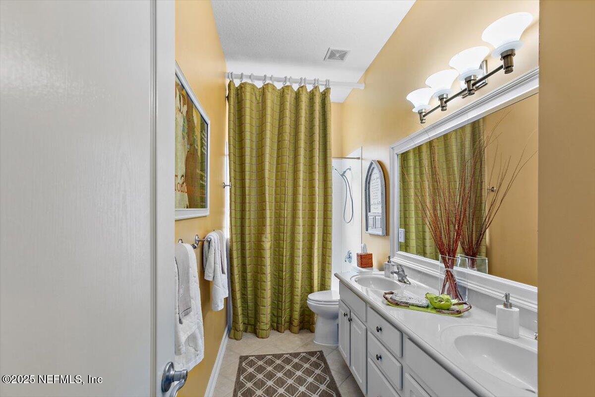 1400 Barrington Circle St. Augustine, FL 32092 - Photo 20 of 45 a bathroom with a double vanity sink a mirror and a shower