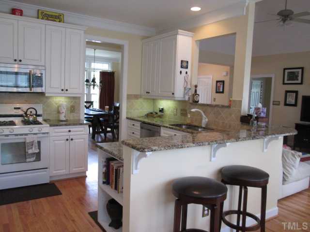 8120 Standing Stone Court Raleigh, NC 27613 - Photo 13 of 25 Another view of the kitchen that features an eat at raised bar, bookcase shelving at end of counter makes a great place for your favorite cookbooks, hardwood flooring, pass thru opening lets you see into the living room!