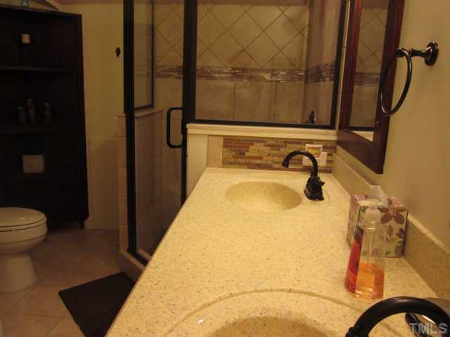 8120 Standing Stone Court Raleigh, NC 27613 - Photo 21 of 25 Another view of the secondary bath upstairs in the bonus space. Double sink vanity with mirrors above both sink spaces, large shower completely tiled with custom tile work and river stone floor in shower!
