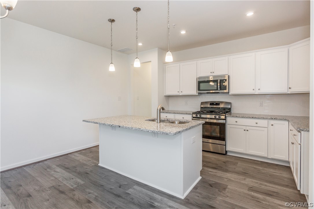 a kitchen with kitchen island a sink stainless steel appliances and white cabinets
