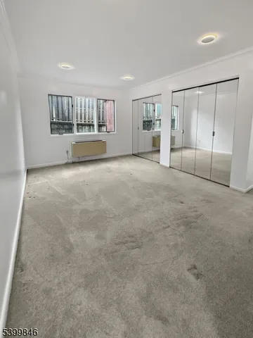 a view of an empty room with a window and cabinet