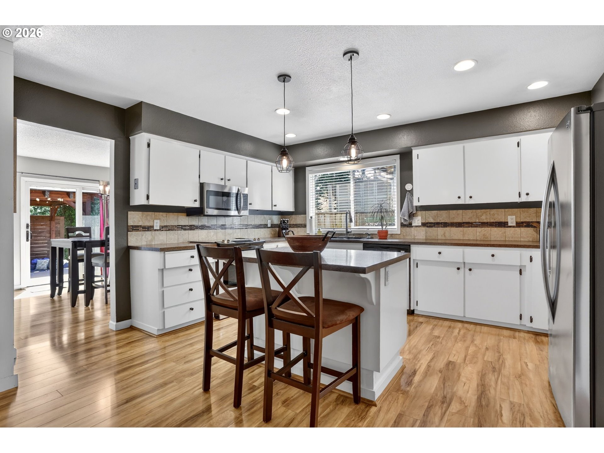 1776 Southeast 114th Place Portland, OR 97216 - Photo 20 of 47 a kitchen with kitchen island granite countertop wooden floors white cabinets and stainless steel appliances