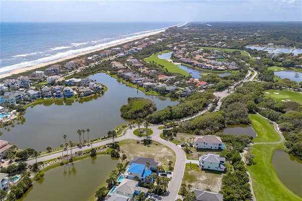 an aerial view of ocean and residential houses with outdoor space